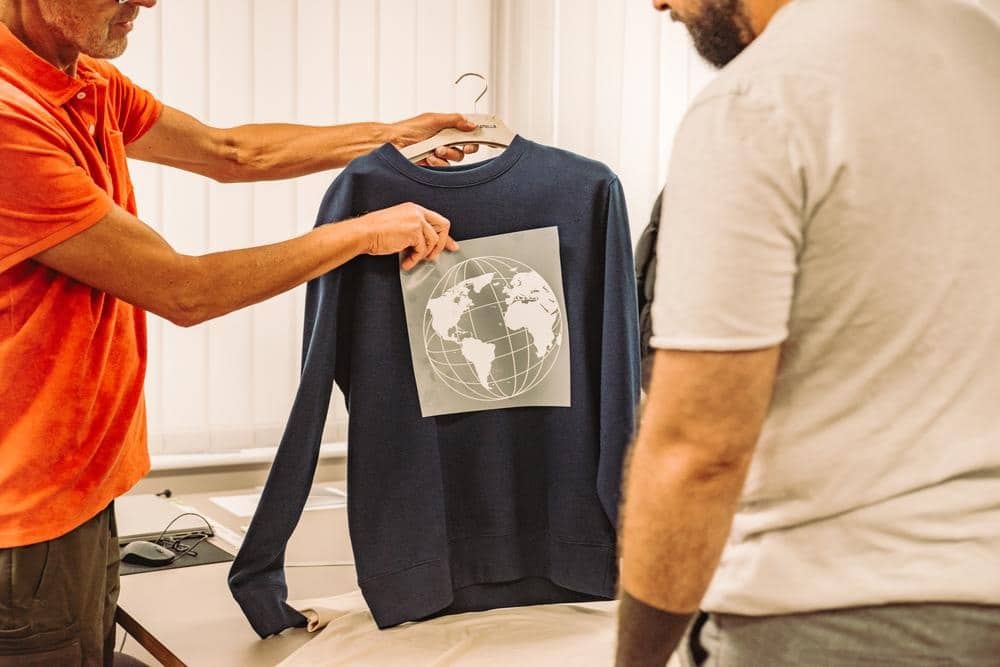 Kundenberatung zu individuell bedrucktem Sweatshirt mit Globus-Motiv.