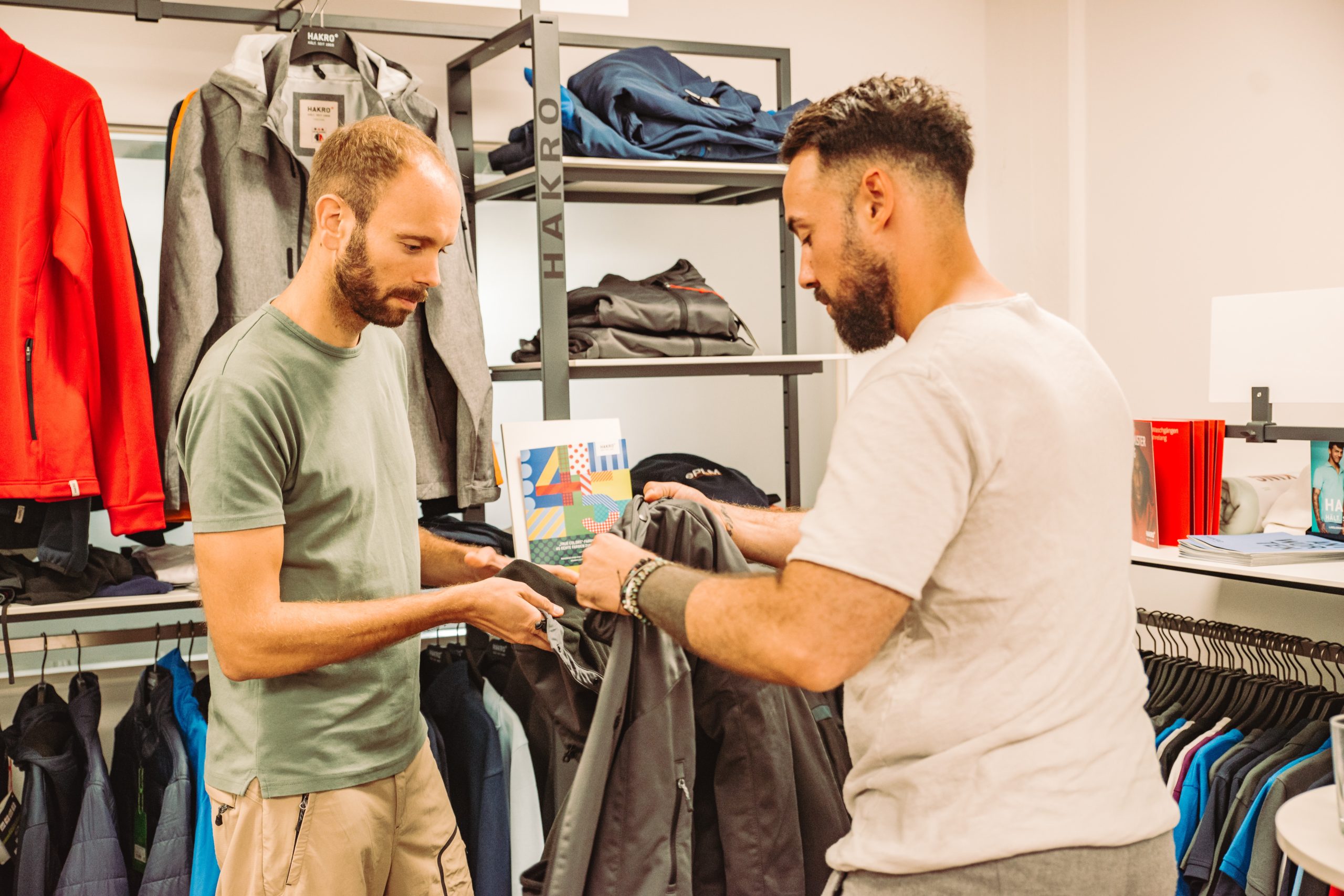 Zwei Männer begutachten eine graue Jacke im Showroom von PTM Protex.
